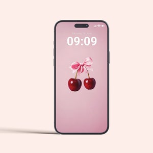 Könnte beinhalten: Ein rosa Smartphone mit schwarzem Rahmen zeigt einen rosa Hintergrund mit zwei roten Kirschen, die mit einem rosa Band zusammengebunden sind. Die Uhrzeit auf dem Bildschirm ist 09:09 und das Datum ist Montag, der 16. Juni.