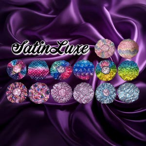 May include: A collection of satin hair bonnets in various colors and patterns, including tie-dye, floral, and solid hues. The bonnets are arranged on a purple satin background, with the text "Satin Luxe" in a cursive font.