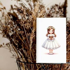May include: A white card with a cartoon illustration of a girl in a white dress and a flower crown holding a book. The girl has brown hair and blue eyes.