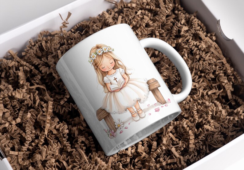 May include: White ceramic mug with a colorful illustration of a girl wearing a white dress and a flower crown, holding a book and sitting on a wooden bench. The girl has long blonde hair and blue eyes. The mug has a handle on the right side.