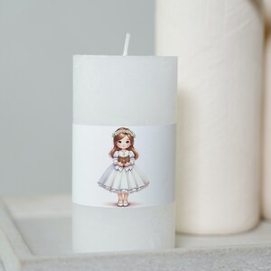May include: White pillar candle with a printed image of a girl in a white dress and a flower crown holding a book. The girl is standing on a white background.