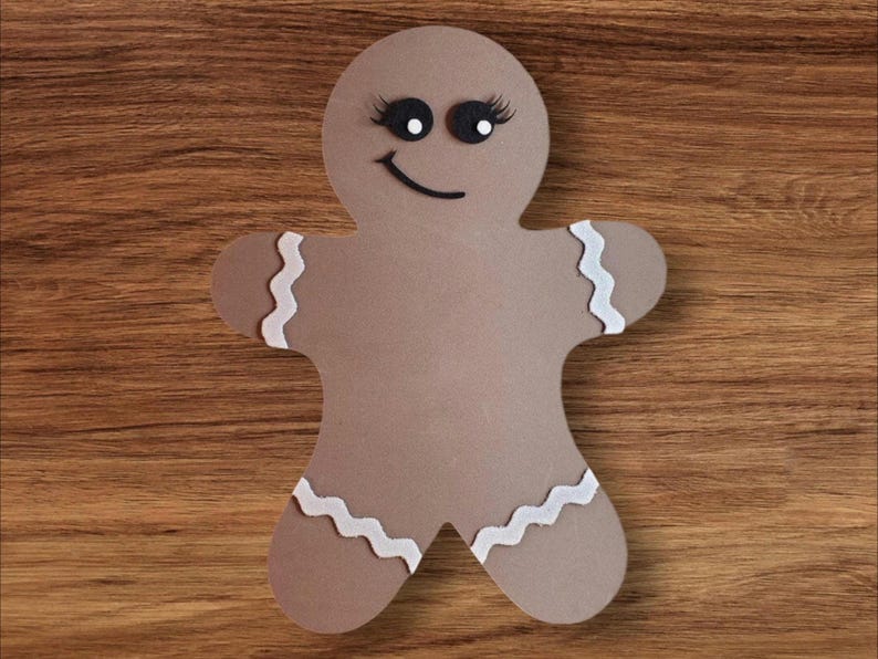 May include: A brown gingerbread person cutout with white icing and black eyes. The gingerbread person is smiling.
