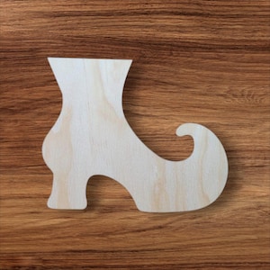 May include: A wooden cutout in the shape of a high-heeled boot. The boot is made of light-colored wood and has a curved heel and a decorative swirl at the top of the boot. The cutout is placed on a brown wooden surface.