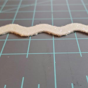 May include: White glitter trim with a wavy edge.