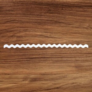 May include: A white zig-zag border trim on a brown wooden surface.