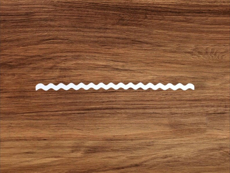 May include: A white zig-zag border trim on a brown wooden surface.