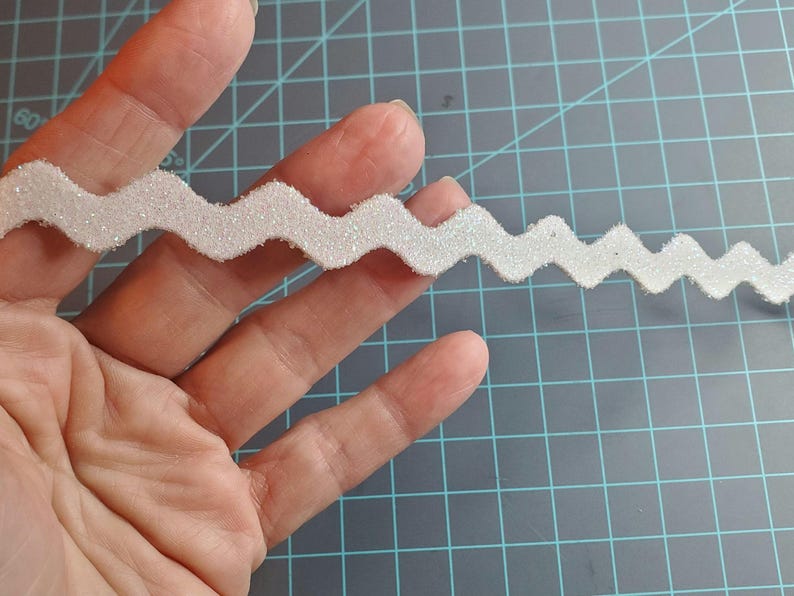 May include: White sparkly zig zag trim with a wavy edge.