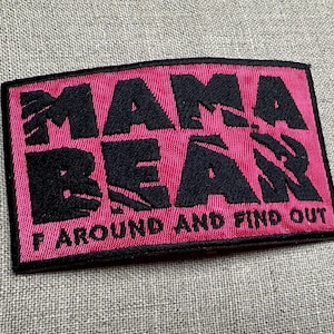 May include: Pink fabric patch with black embroidered text that reads "Mama Bear F around and find out".