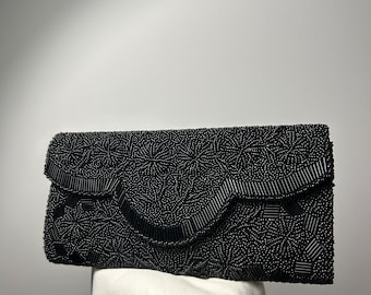 Vintage women’s black beaded clutch, hand-sewn beads, lined in black satin and has a front snap closure. 1960s, perfect condition.