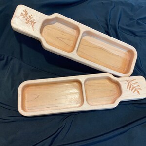 May include: Two wooden serving trays with a divided compartment. Each tray has a carved leaf design on the handle.