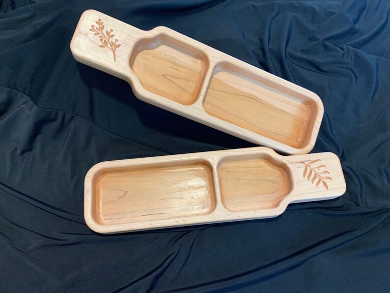 May include: Two wooden serving trays with a divided compartment. Each tray has a carved leaf design on the handle.