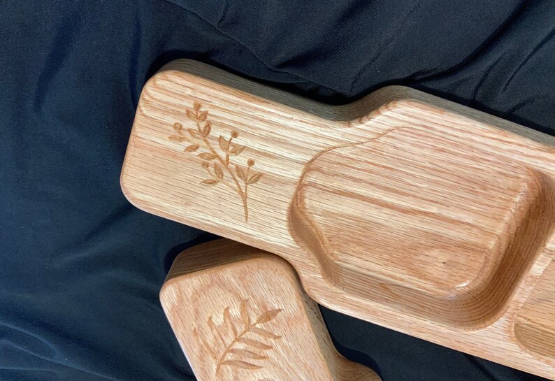 May include: A wooden serving tray with three compartments, each with a unique shape. The tray is made of light brown wood and has a natural finish. The tray is decorated with a simple floral design.