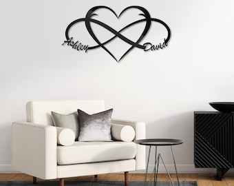 May include: Black metal wall art featuring an infinity symbol intertwined with a heart. The names "Ashley" and "David" are written on either side of the heart.