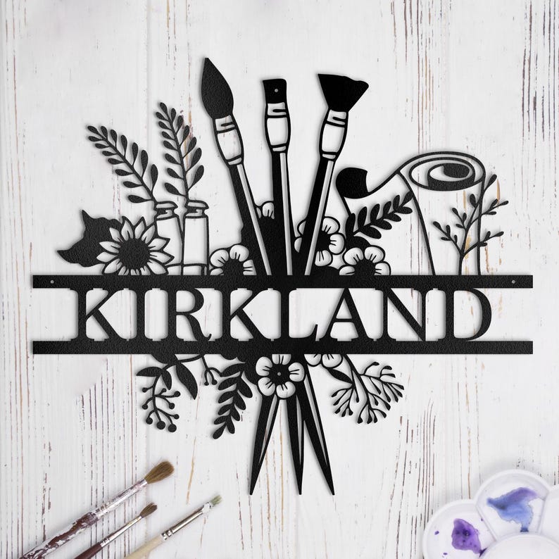 May include: Black metal art piece with the name "KIRKLAND" in a decorative font. The art features three paintbrushes, a paint roller, and floral designs.