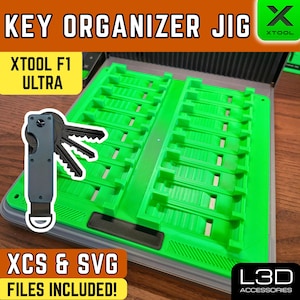 Puede incluir: Una plantilla organizadora de llaves verde con el texto "KEY ORGANIZER JIG" y "XTOOL F1 ULTRA". La plantilla incluye ranuras para llaves y un llavero. La imagen también incluye el texto "XCS & SVG FILES INCLUDED!"