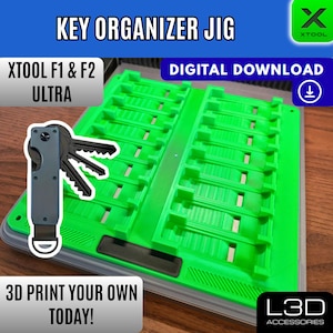 Könnte beinhalten: Eine leuchtend grüne Schlüsselorganisationsvorrichtung mit dem Text "KEY ORGANIZER JIG" und "DIGITALER DOWNLOAD". Das Bild zeigt auch einen Schlüsselhalter mit Schlüsseln und dem Text "XTOOL F1 & F2 ULTRA". Der Text "DRUCKE DEIN EIGENES HEUTE!" ist ebenfalls sichtbar.