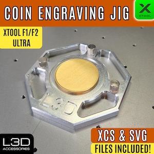 Könnte beinhalten: Eine silberne Münzgravurvorrichtung mit einer goldenen Münze in der Mitte. Die Vorrichtung ist für XTOOL F1/F2 ULTRA Maschinen konzipiert. Der Text "COIN ENGRAVING JIG" und "XCS & SVG FILES INCLUDED!" sind sichtbar.