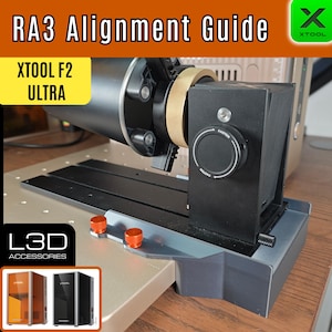 May include: An RA3 Alignment Guide with the text "RA3 Alignment Guide" and "XTOOL F2 ULTRA". The device is black with a gold-colored ring and orange adjustment knobs. The L3D Accessories logo is visible.