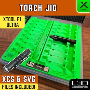 May include: A green Torch Jig with the text "TORCH JIG" and "XTOOL F1 ULTRA". The jig includes a black flashlight and the text "XCS & SVG FILES INCLUDED!". The L3D Accessories logo is visible.