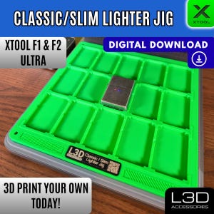 May include: A green 3D-printed jig for classic and slim lighters, with a lighter in place. Text includes "CLASSIC/SLIM LIGHTER JIG", "XTOOL F1 & F2 ULTRA", "DIGITAL DOWNLOAD", and "3D PRINT YOUR OWN TODAY!"