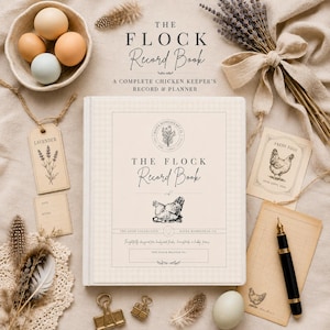 May include: A cream-coloured hardcover record book titled The Flock Record Book with a chicken illustration, surrounded by a bowl of eggs, lavender sprigs, a fountain pen, paper tags, and metal clips on a textured fabric surface.