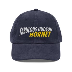 May include: A navy blue corduroy baseball cap with white embroidered text that reads "Fabulous Hudson Hornet" in a yellow outline.