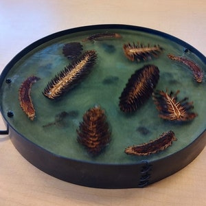 Hand made epoxy resin charcuterie tray with pinecones.  This is a hand made epoxy charcuterie board with handles.  It is food safe.