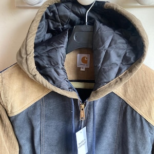 May include: A Carhartt corduroy jacket in shades of brown, tan, and blue, with a quilted black hood lining. The jacket has a full zipper, a tag that reads "beldi's vintage", and a Carhartt label.