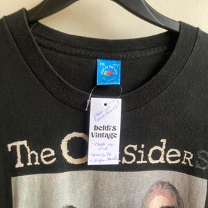 May include: Black t-shirt with a band graphic. The shirt has the text "The C Sider S" in a distressed font. A tag reads "beldi's Vintage" and "Made in USA". The shirt is size XXL and is hanging on a black hanger.