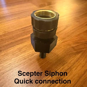 May include: A black and gold Scepter Siphon quick connection fitting. The fitting has a hexagonal base and a threaded top with gold accents. The text "Scepter Siphon Quick connection" is printed on the surface.