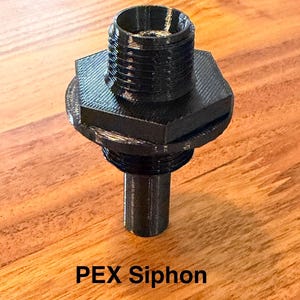 Op de afbeelding: Een zwarte PEX-sifon met een schroefdraad aan de bovenkant, een zeshoekige basis en een cilindrische steel. De tekst "PEX Siphon" staat onderaan de afbeelding. Het object is gemaakt van een 3D-geprint materiaal.