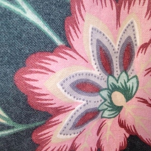 Puede incluir: Primer plano de una tela floral con un fondo verde azulado oscuro. El diseño presenta una gran flor rosa con acentos rojos y crema. También se ven hojas verdes y flores más pequeñas.