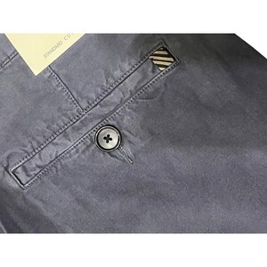 Puede incluir: Primer plano de un pantalón gris. El pantalón tiene cierre de botón, un bolsillo trasero con diseño de rayas y costuras visibles. Una etiqueta con el texto "STANDARD CU." está adjunta.