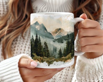 May include: White ceramic mug with a watercolor design of a mountain range with fog and trees. The mug has a handle on the right side.