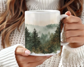 May include: White ceramic mug with a watercolor design of a misty forest scene. The design features a variety of green trees and a soft, hazy background.