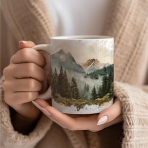 a woman holding a coffee mug with a mountain scene on it