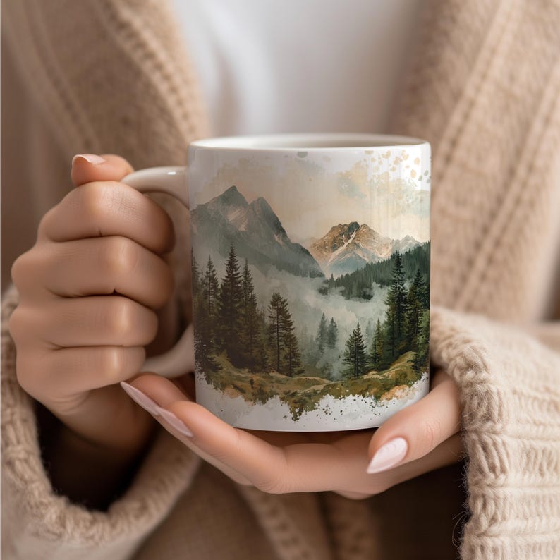 a woman holding a coffee mug with a mountain scene on it