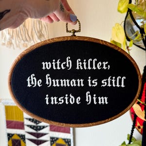 Könnte beinhalten: Eine weiße Keramik-Tasse mit schwarzem Henkel und dem Text "But First, Coffee" in schwarzer, handschriftlicher Schrift. Die Tasse steht auf einer weißen Oberfläche.
