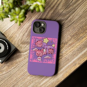 May include: Purple phone case with a pink and white design featuring cartoon pigs with hearts and stars.