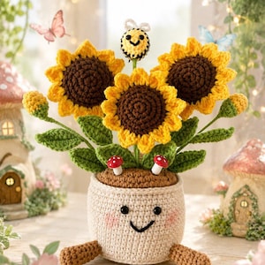 May include: A crocheted potted plant featuring three yellow sunflowers with brown centers, green leaves, and a small bee on top. The beige pot has a smiling face with pink cheeks and two brown legs, accented by two small red and white mushrooms.