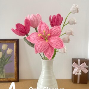 May include: A white ceramic vase holds a bouquet of handmade crochet flowers. The bouquet includes pink lilies, tulips, and white bell-shaped flowers. The text "A - Only Flowers" is visible in the image.