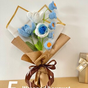 May include: A handcrafted crochet bouquet featuring blue, white, and orange flowers. The bouquet is wrapped in brown paper and tied with a brown ribbon. The text "E - Wrapped bouquet" is visible on the lower left.