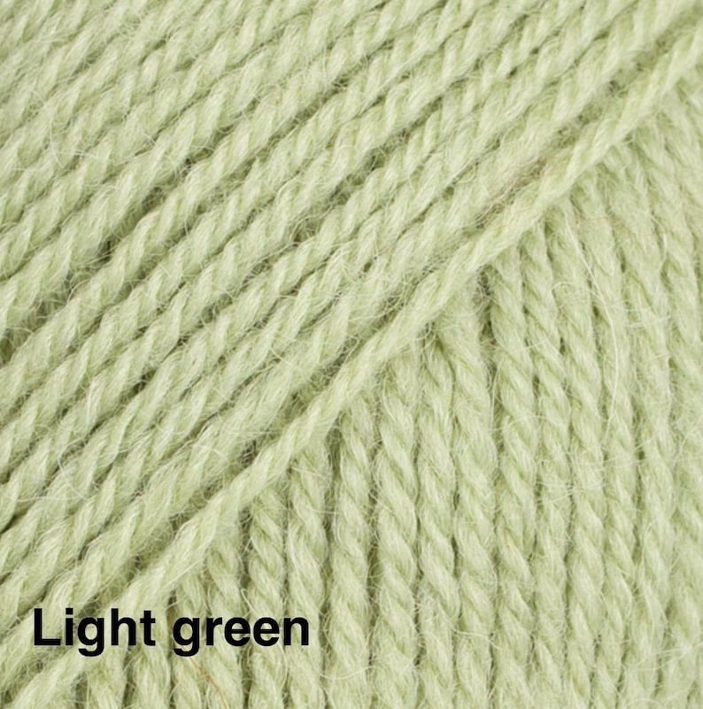 May include: A close-up view of light green yarn featuring a multi-ply twisted fibre construction. The texture shows individual strands of the yarn running diagonally across the frame, with the text Light green printed in the bottom left corner.