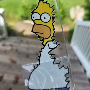 May include: A yellow cartoon character with blue pants and a white shirt. The character has a yellow head with two large eyes and a black outline. The character is looking to the left.