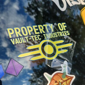 May include: A yellow and black Vault-Tec Industries sticker with the text "Property of Vault-Tec Industries" and a stylised atomic symbol.