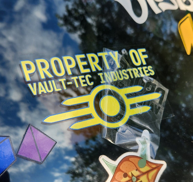 May include: A yellow and black Vault-Tec Industries sticker with the text "Property of Vault-Tec Industries" and a stylised atomic symbol.