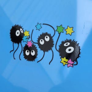 May include: Five black fuzzy creatures with large eyes and long legs are holding colorful stars on a light blue background.