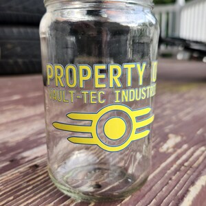 May include: A clear glass jar with a yellow and blue Vault-Tec Industries logo that says "PROPERTY OF VAULT-TEC INDUSTRIES".