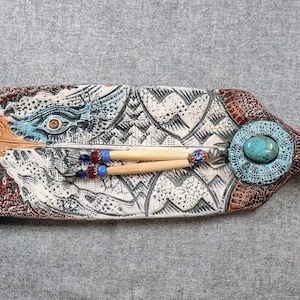 May include: A ceramic serving tray with a painted design of an eagle's head and feathers. The tray has a brown, white, and blue color scheme and features a turquoise stone accent.