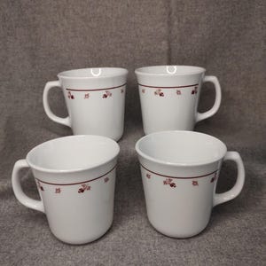 Könnte beinhalten: Ein Set aus drei Keramikbechern mit gesprenkelter, matter Oberfläche. Die Becher sind in den Farbtönen Creme, Hellbraun und Dunkelbraun gehalten. Jeder Becher hat ein schlichtes, minimalistisches Design und einen abgerundeten Griff.